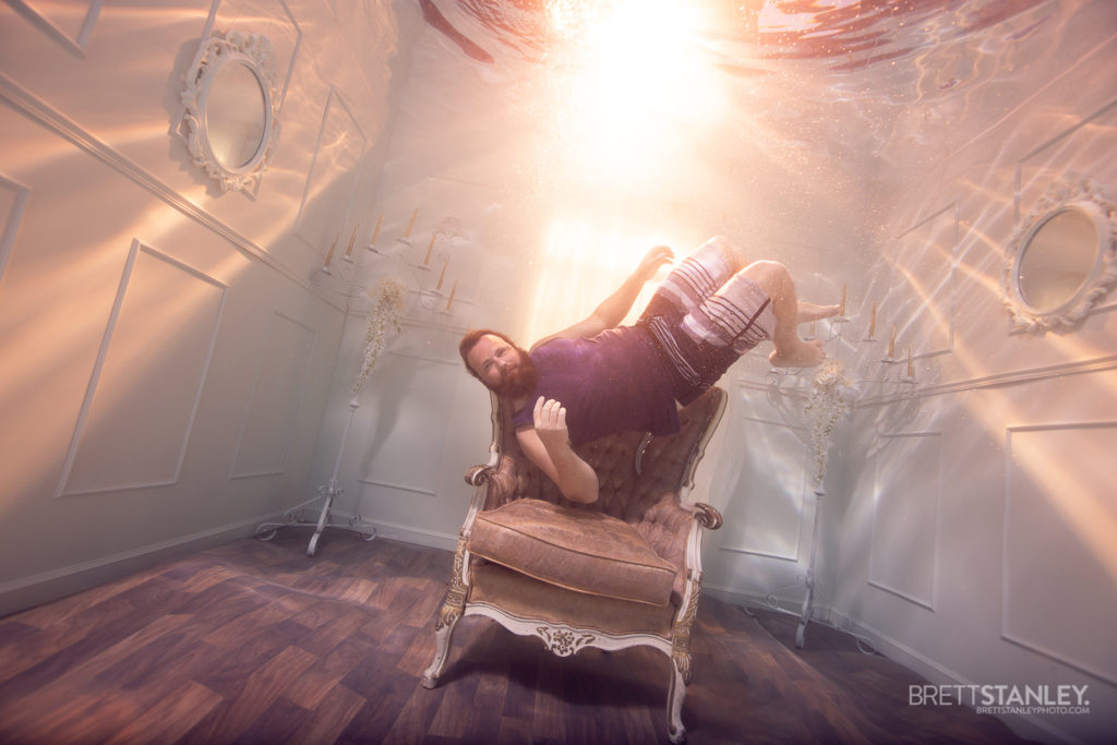 bearded man floating in an underwater room with sunset